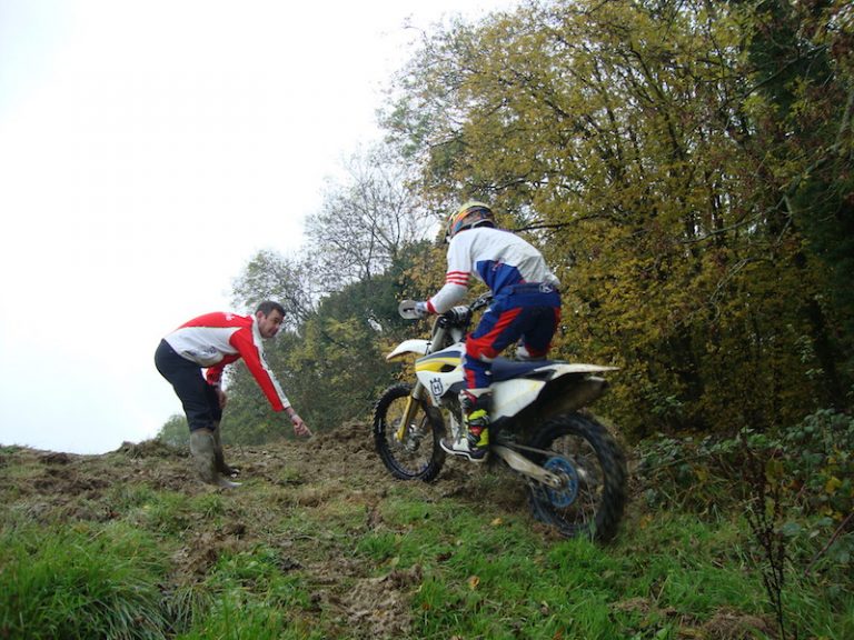 An instructor shows a rider how to ride a motorcycle up a steep slope