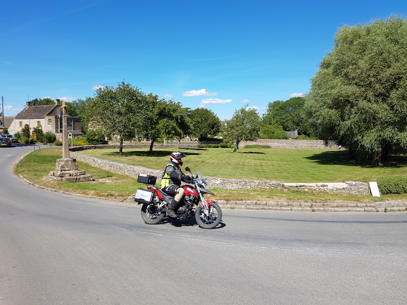 A 125cc motorcycle riding through a cotswold villiage