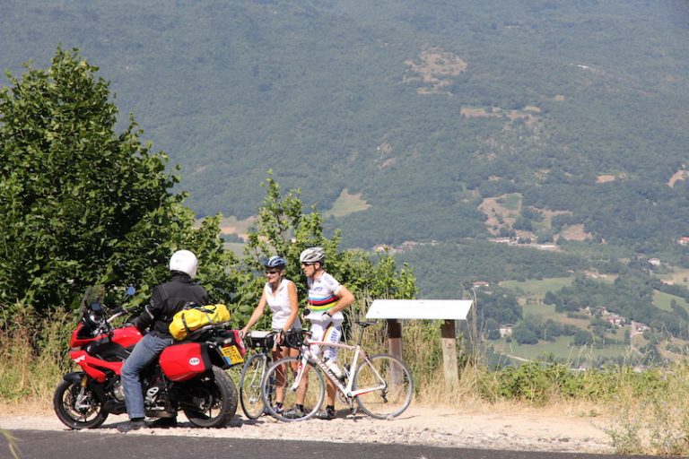 A motorcyclist talking to two cyclists
