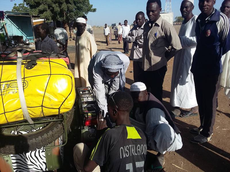 A group of men fixing a side car motorcycle in Africa