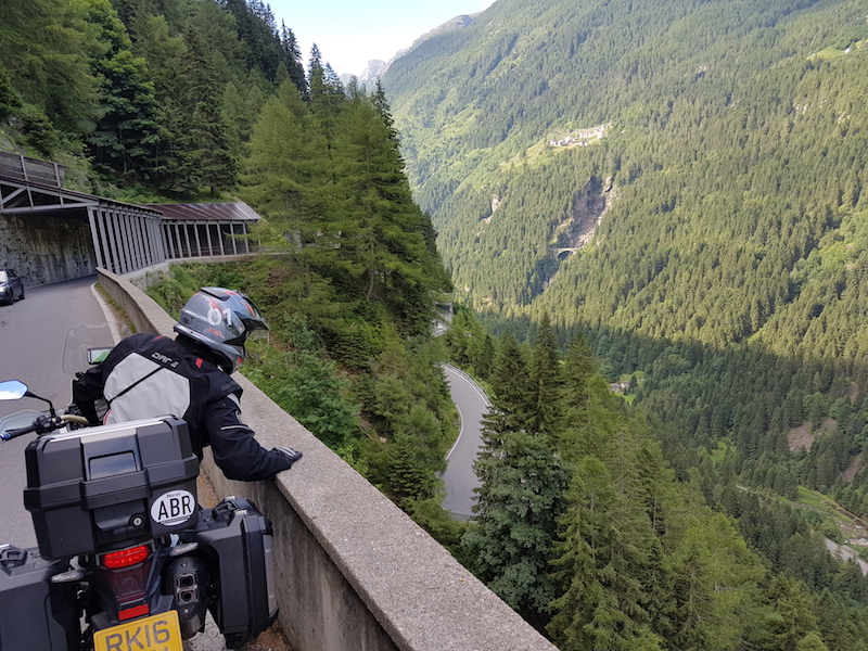 A Motorcyclist looks over a protective barrier on the splugen pass